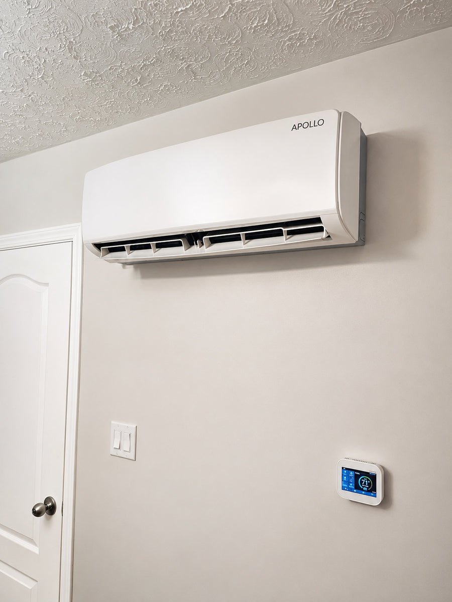 Apollo 1.5 ton wall fan coil installed above a thermostat with its air louvers open.