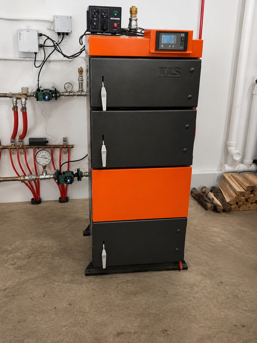 Black and orange boiler installed in a mechanical room with wall-mounted hydronic manifold, pumps, and control panel.