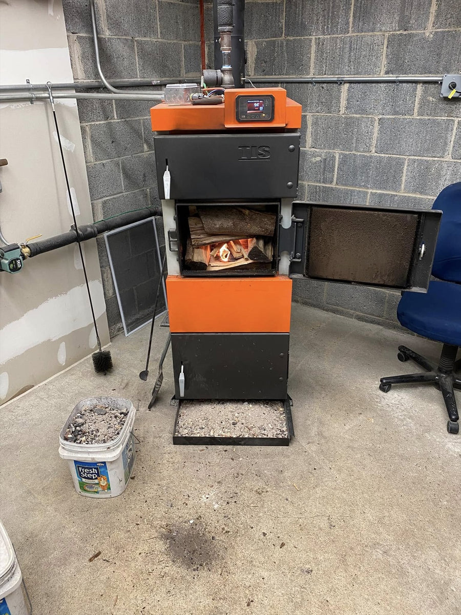UNI wood boiler with its firebox door open, loaded logs, and a small flame inside.